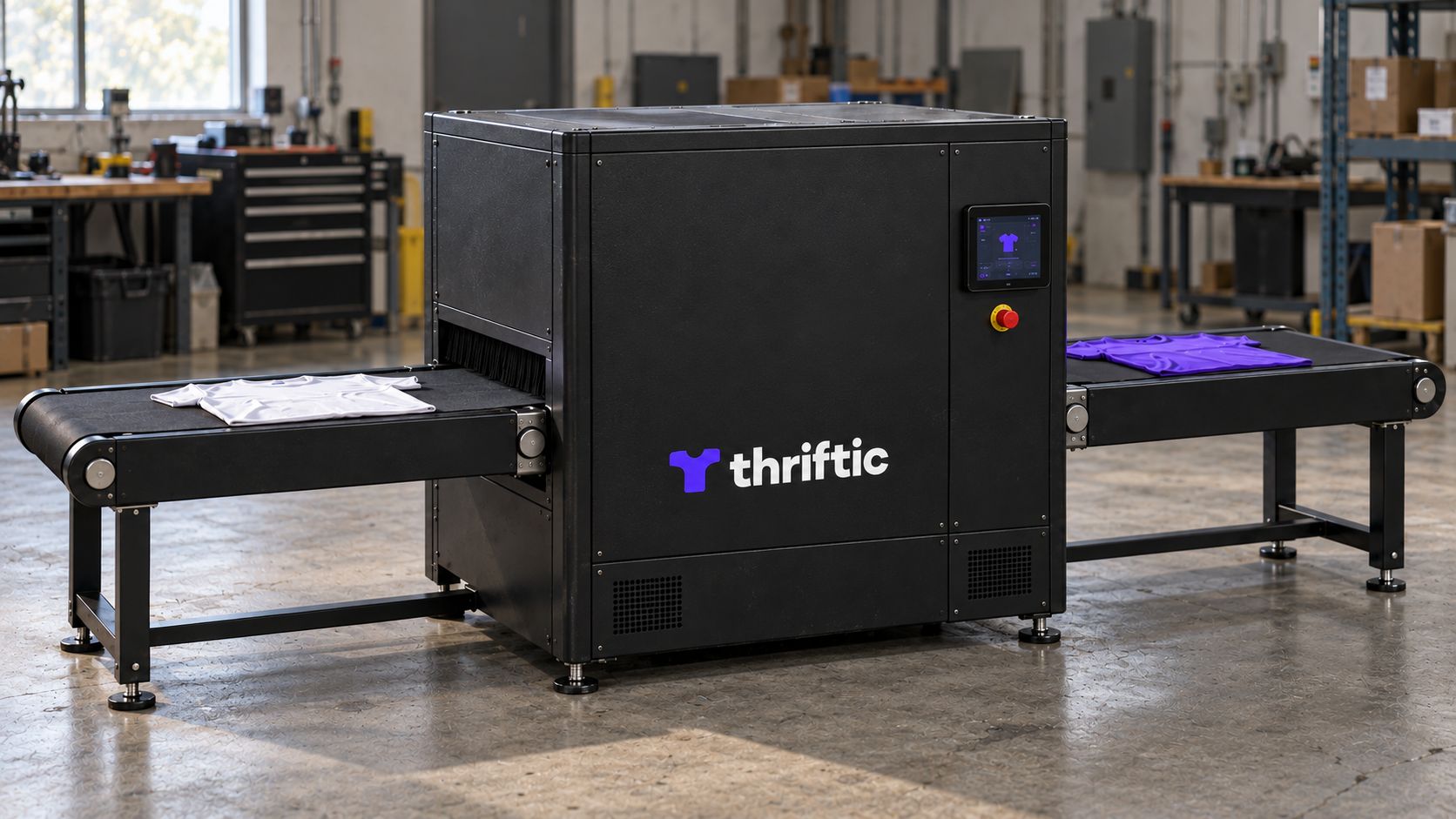 Thriftic prototype concept in a workshop, with textured black panels, a small violet and white logo low on the front door, and garments on the conveyor belts.